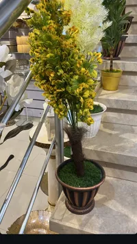 نبات زينة صناعي بأزهار صفراء مع إناء