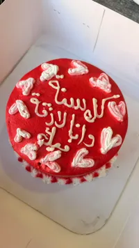 كيكة حمراء مزينة بالقلوب والكريمة البيضاء
