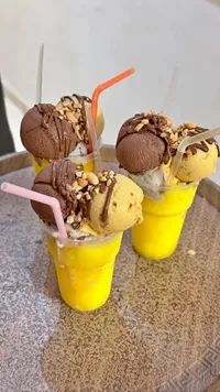 كوب مثلجات مشكل مع صوص الشوكولاتة والمكسرات