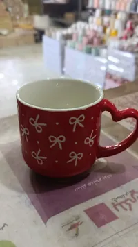 مج سيراميك أحمر بنقوش فيونكات ومقبض على شكل قلب