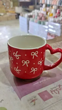 مج سيراميك أحمر بنقوش فيونكات ومقبض على شكل قلب
