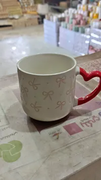 مج سيراميك بنقوش فيونكات ومقبض قلب أحمر